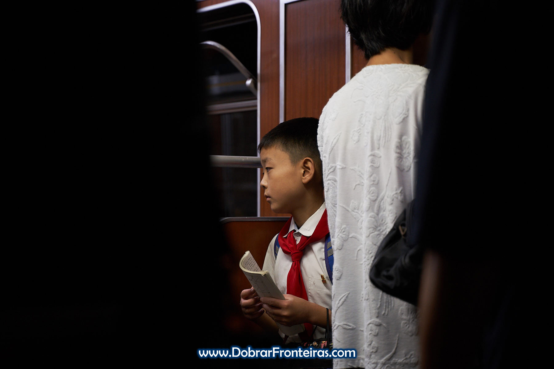 Criança com lenço vermelho de pioneiro no metro de Pyongyang, Coreia do Norte