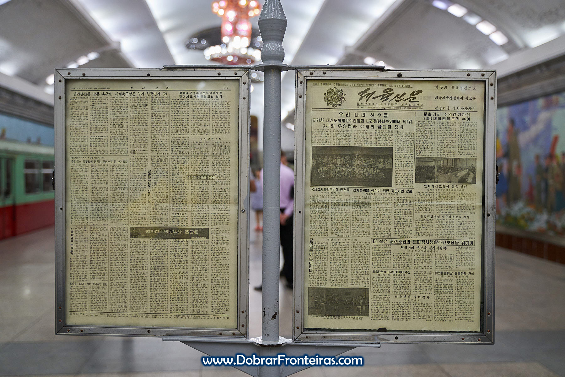 Painel com jornal no metro de Pyongyang