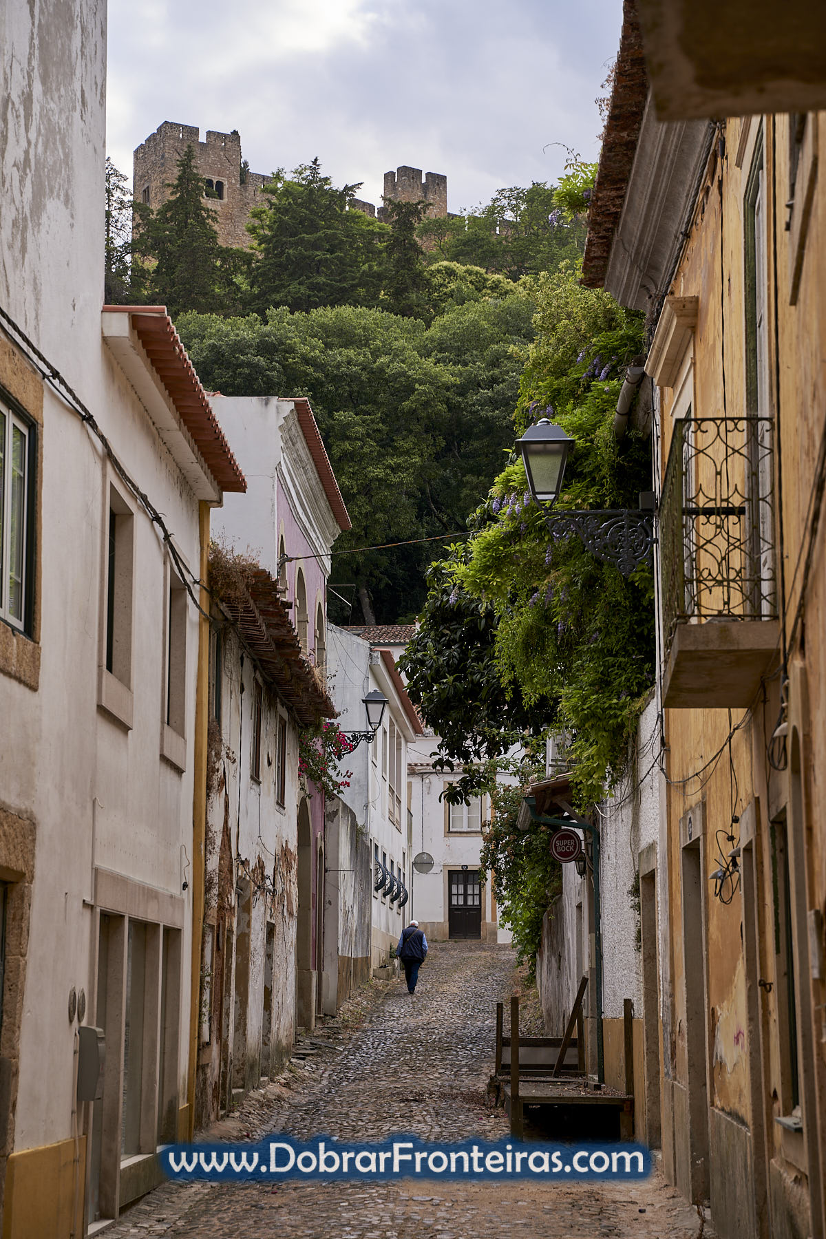 homem a caminhar nem rua de Tomar com castelo
